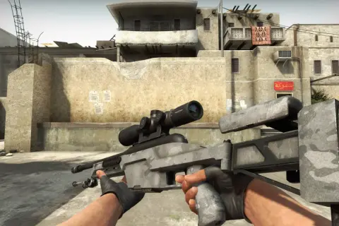 Gracz trzyma karabin snajperski Scout w CS:GO, gotowy do akcji na pustynnej mapie.