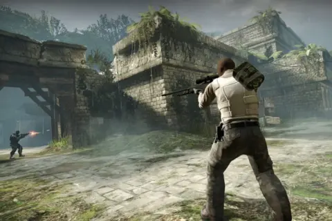 Gracz z karabinem snajperskim w ruinach, gotowy do walki. Dowiedz się, jak włączyć konsolę w CS: GO, by usprawnić rozgrywkę.