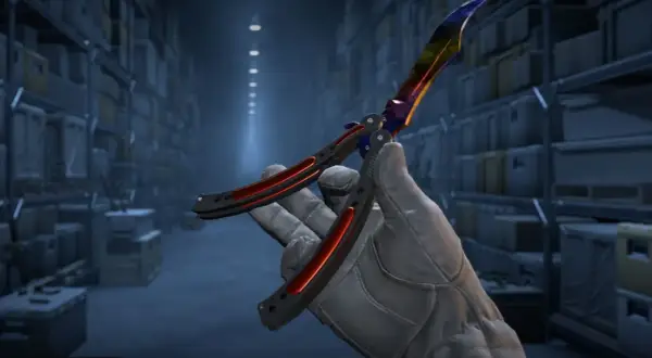 Ręka w rękawiczce trzyma kolorowy nóż motylkowy, gotowy do wykonania **knife command** w magazynie.