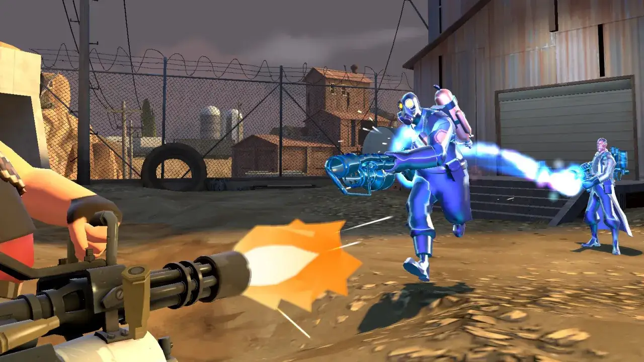 Medic TF2 w akcji! Jeden gracz strzela z miniguna, podczas gdy drugi, w niebieskim kombinezonie, ucieka przed strumieniem energii.