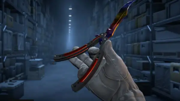 Ręka w rękawiczce trzyma kolorowy nóż motylkowy, gotowy do wykonania **knife command** w magazynie.